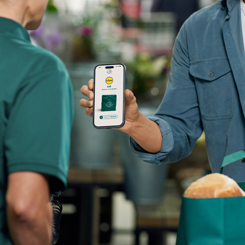 a man holding a cell phone next to a too good to go bag