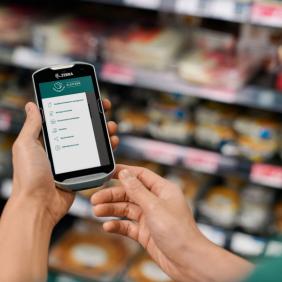 a person is holding a cell phone in their hand in a grocery store .