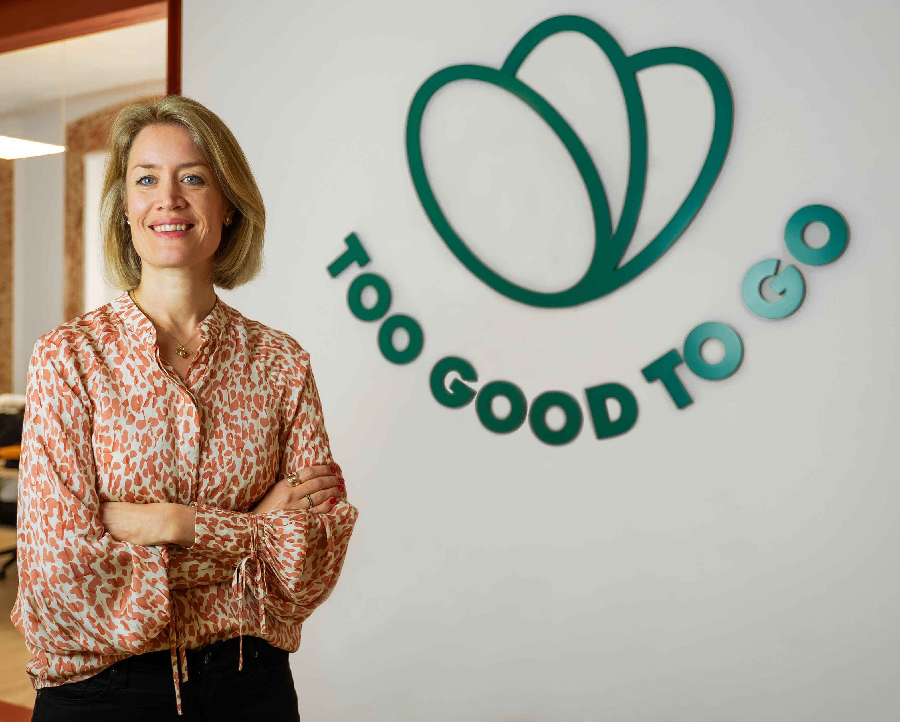 a woman stands in front of a sign that says too good to go