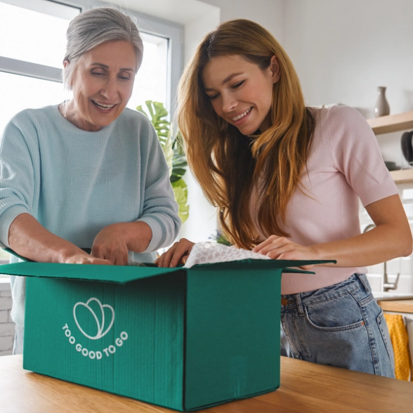 two women are opening a box that says too good to go