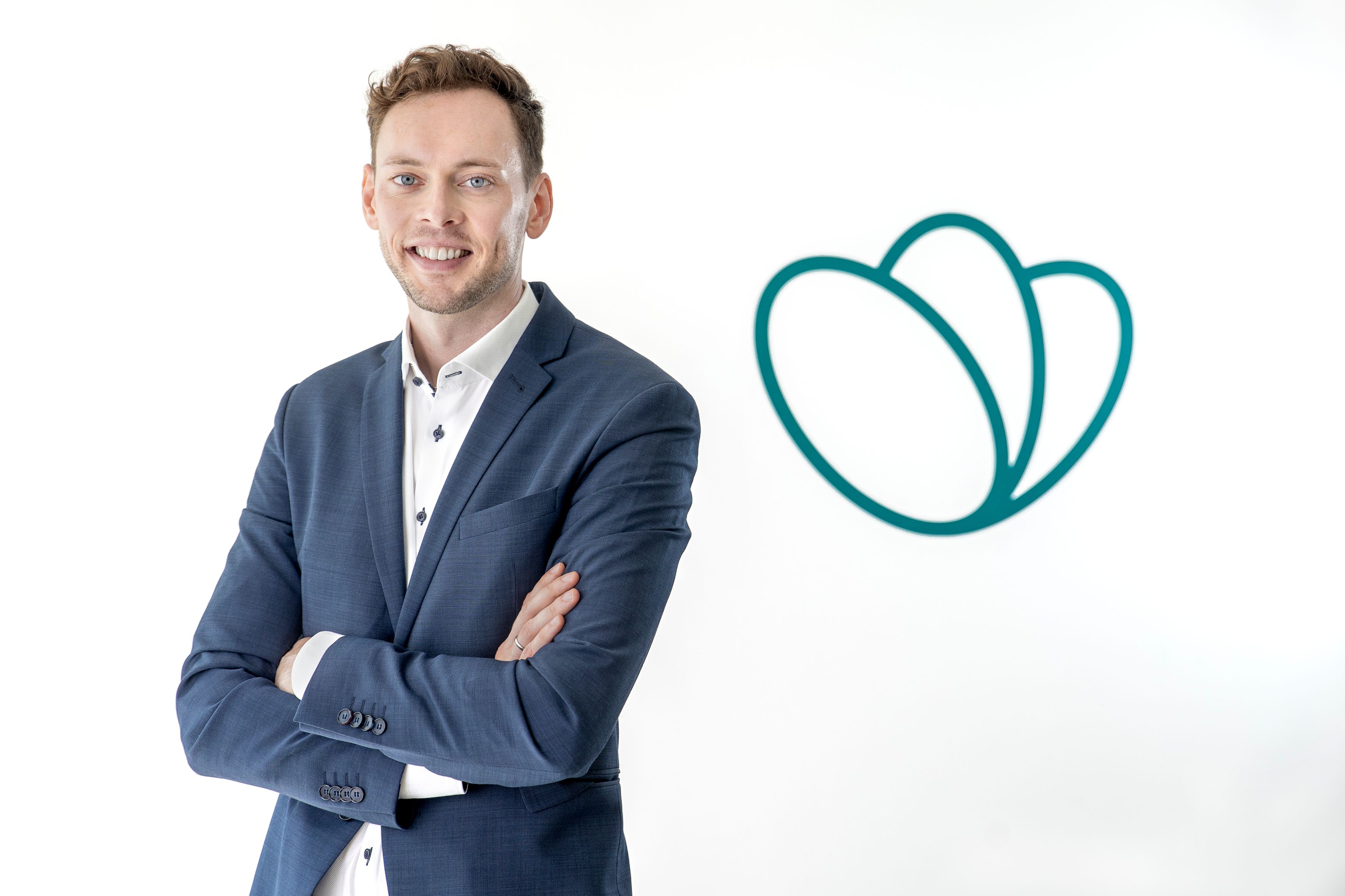 a man in a suit is standing with his arms crossed in front of TGTG logo