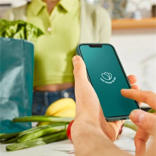 a person holding a cell phone that says too good to go