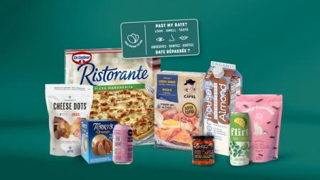An assortment of packaged food and drink products, including pizza, snacks, and drinks, alongside a sign reading "Past my date? Look - Smell - Taste."