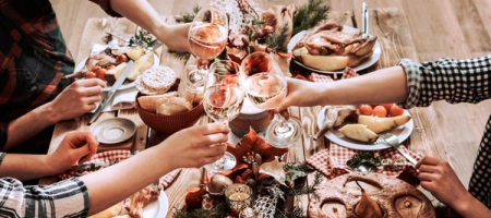 Overhead view of a festive dining table set with a greenery centerpiece, lit candles, multiple food dishes, and place settings.