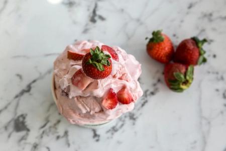 a bowl of strawberry ice cream with strawberries on top on a table .