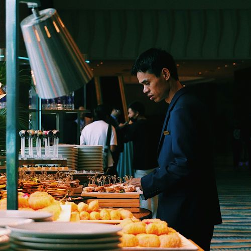 un homme se tient devant une table de buffet avec des assiettes de nourriture
