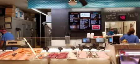 the inside of a seafood market with a menu on the wall .