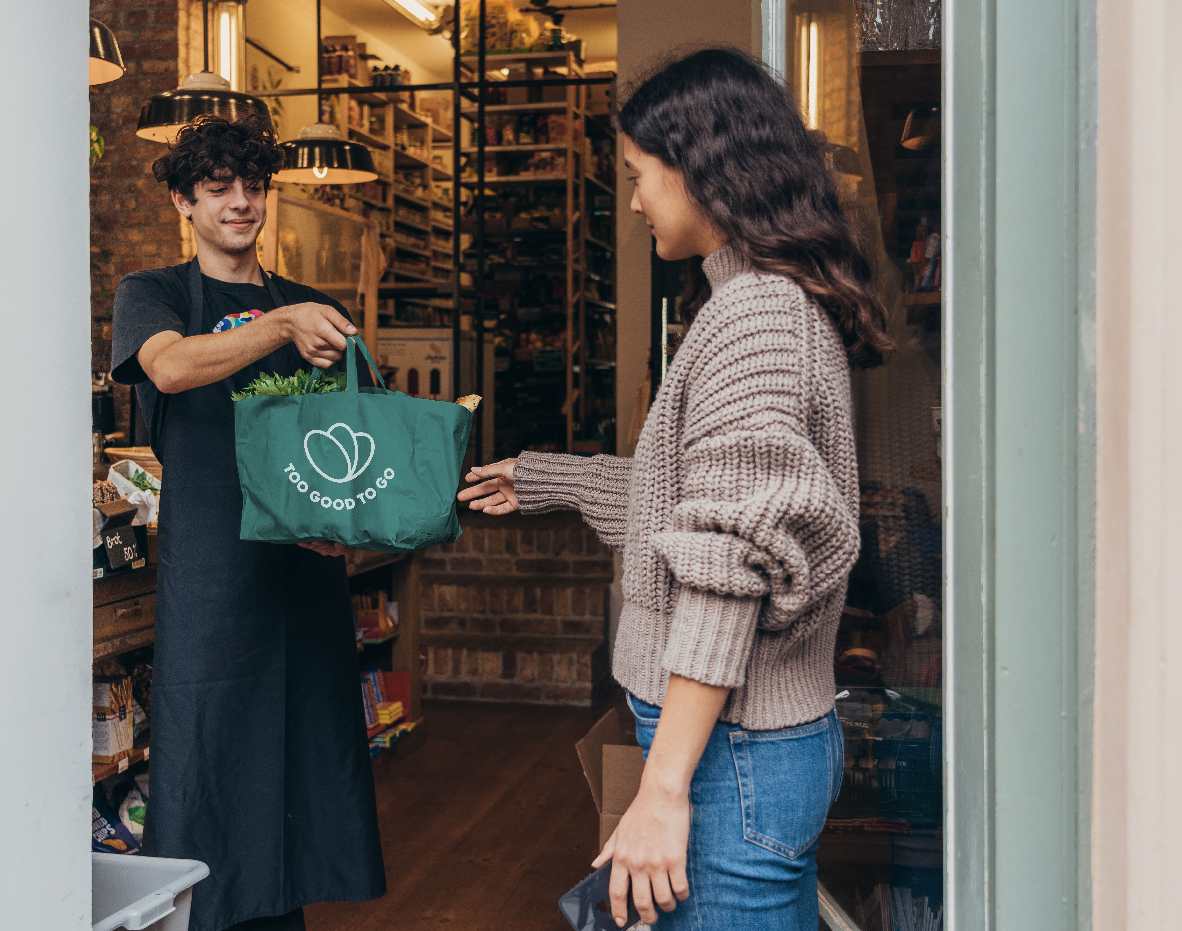 a man is giving a green bag to a woman in a store .