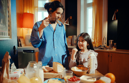 a woman drinking a cup of coffee while a little girl looks on