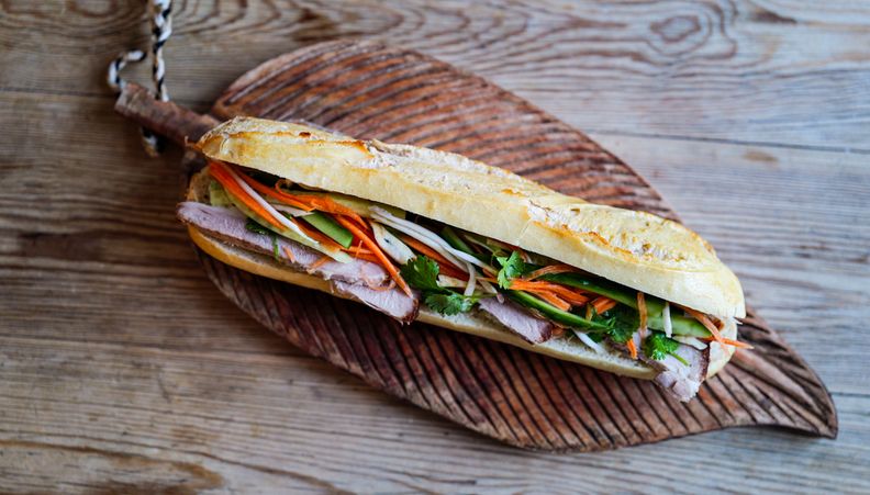 Pork rib stir-fry with green vegetables, red chilies, and cashews, served on a white plate with red chopsticks.