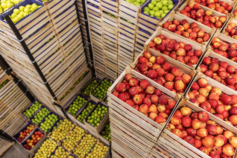 Red, green, and yellow apples in stacked wooden crates.