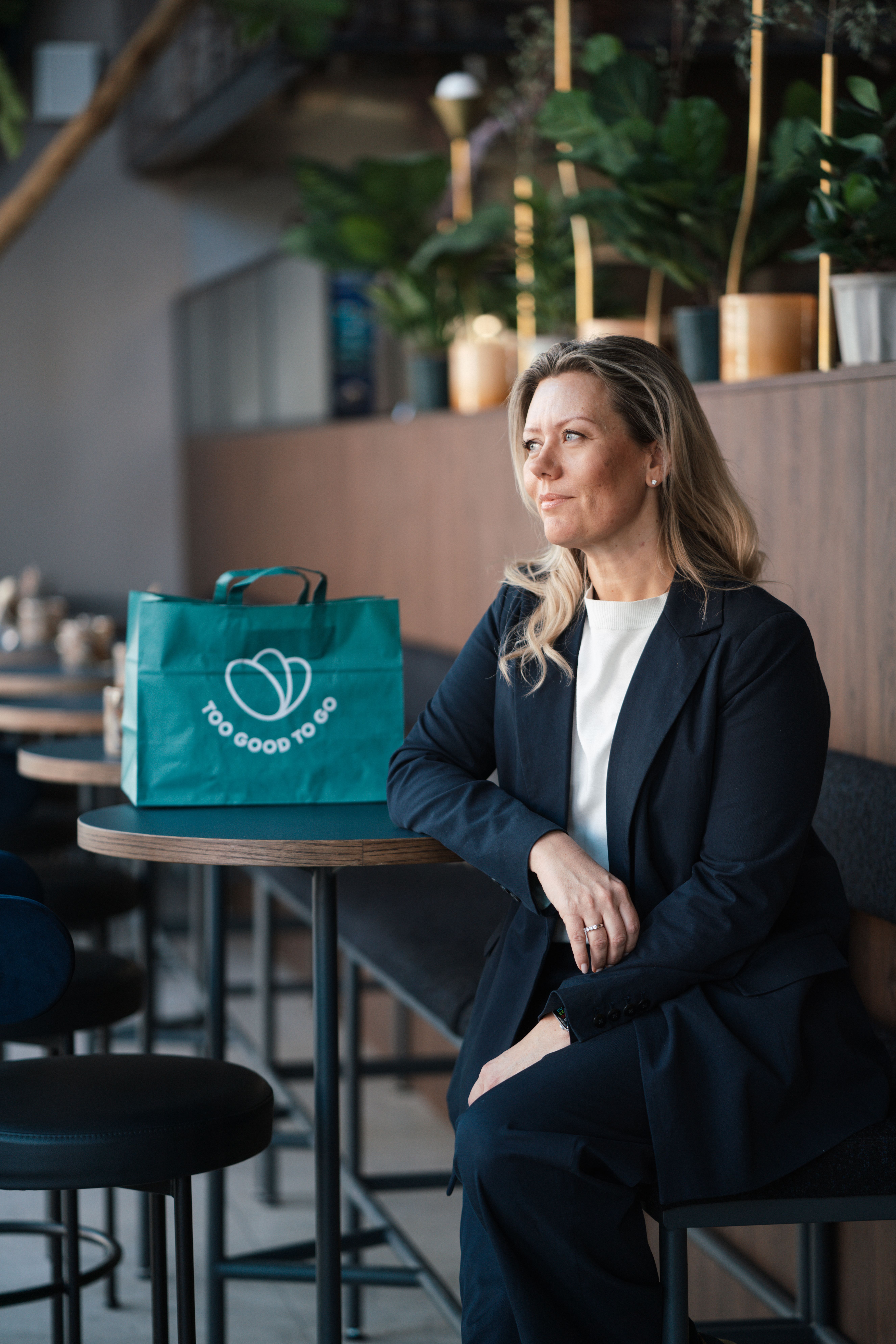 a woman sits at a table with a bag that says too good to go