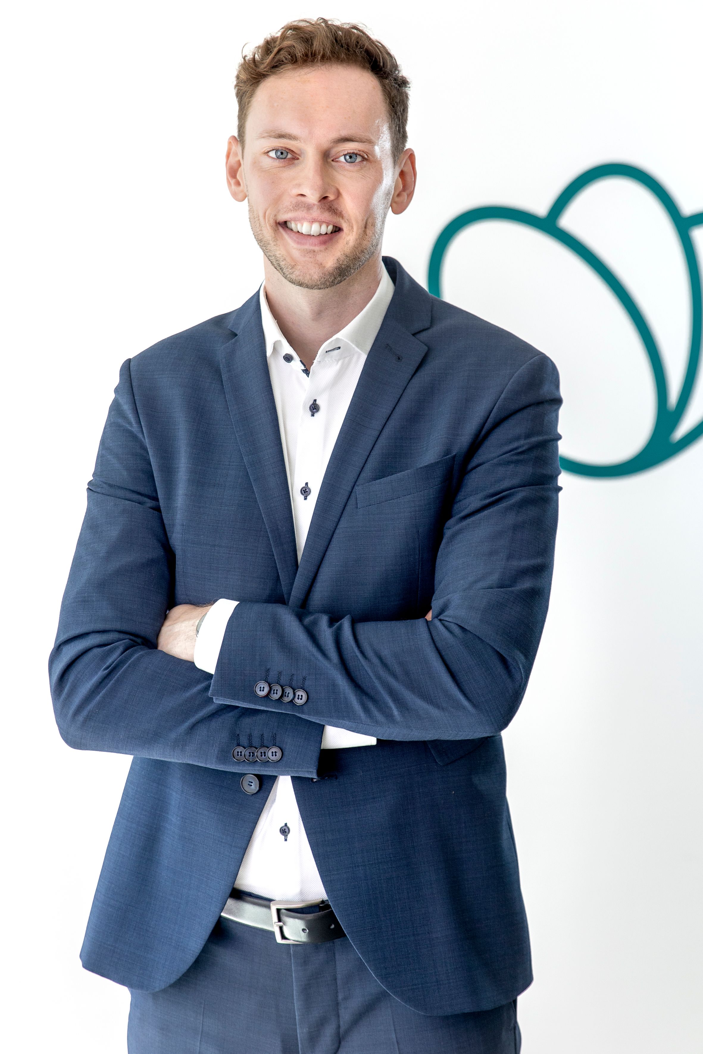 a man in a suit has his arms crossed and is smiling