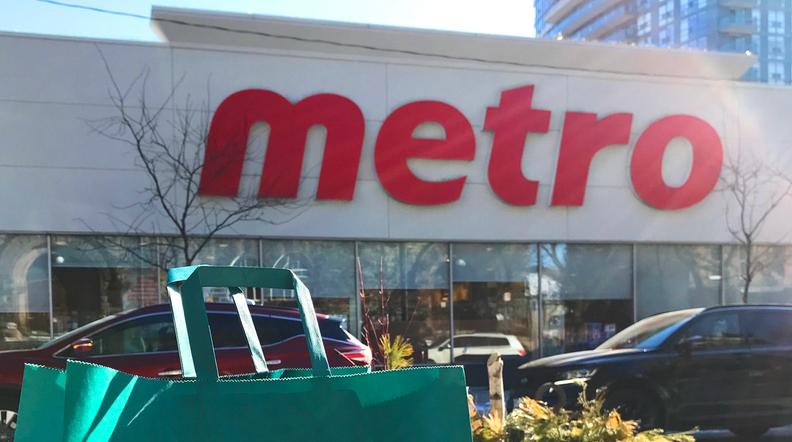 a green too good to go bag sits on a table in front of a metro store