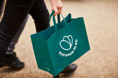 a person is carrying a green bag that says `` too good to go '' .