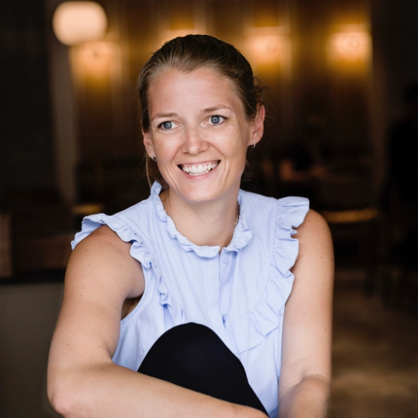 a woman in a blue ruffled top smiles for the camera