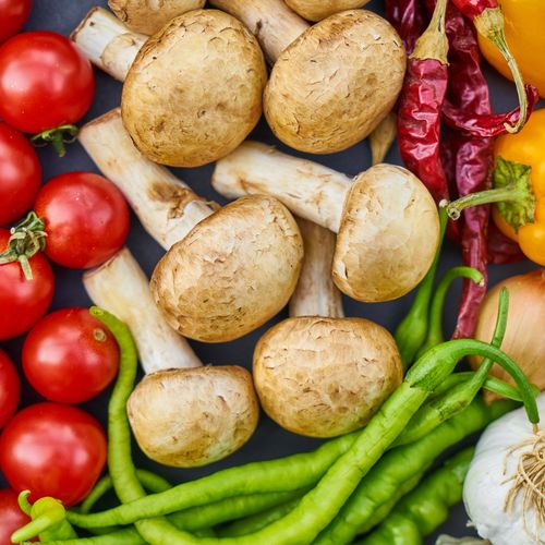 a pan filled with tomatoes , mushrooms , peppers , onions , garlic and other vegetables .