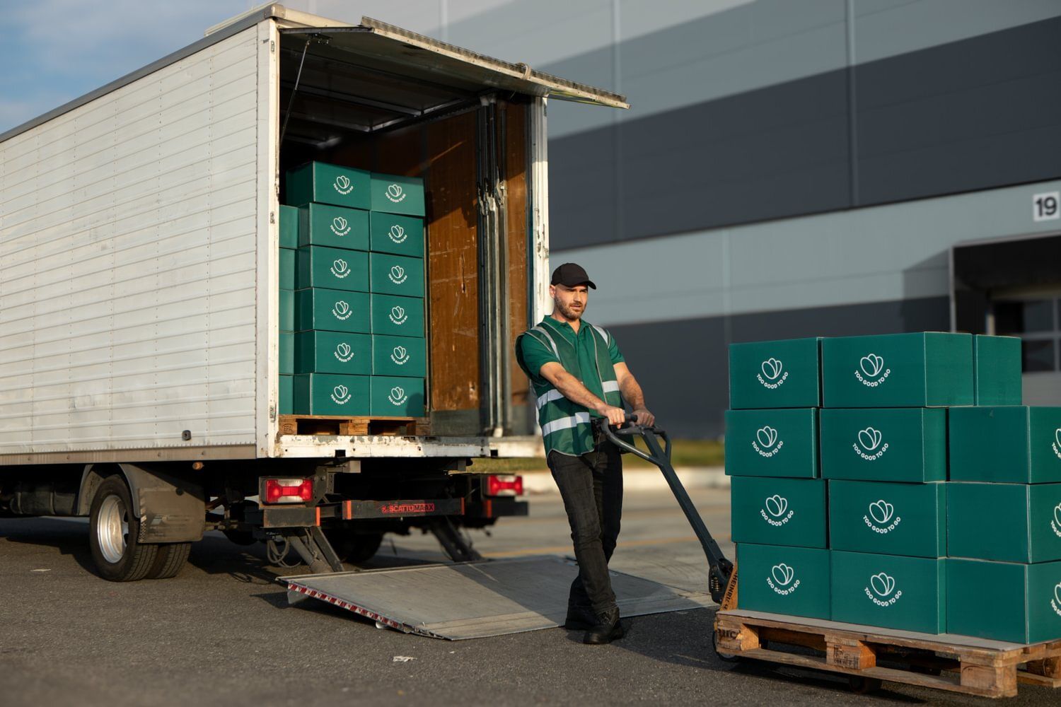 a person holding a shopping cart containing a lemon, a water bottle and other grocery items, picking up greens from the supermarket shelves