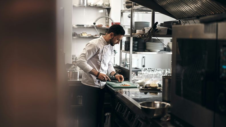un cuoco che prepara un piatto in una cucina professionale