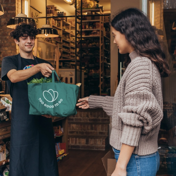 a man is giving a green bag to a woman in a store .