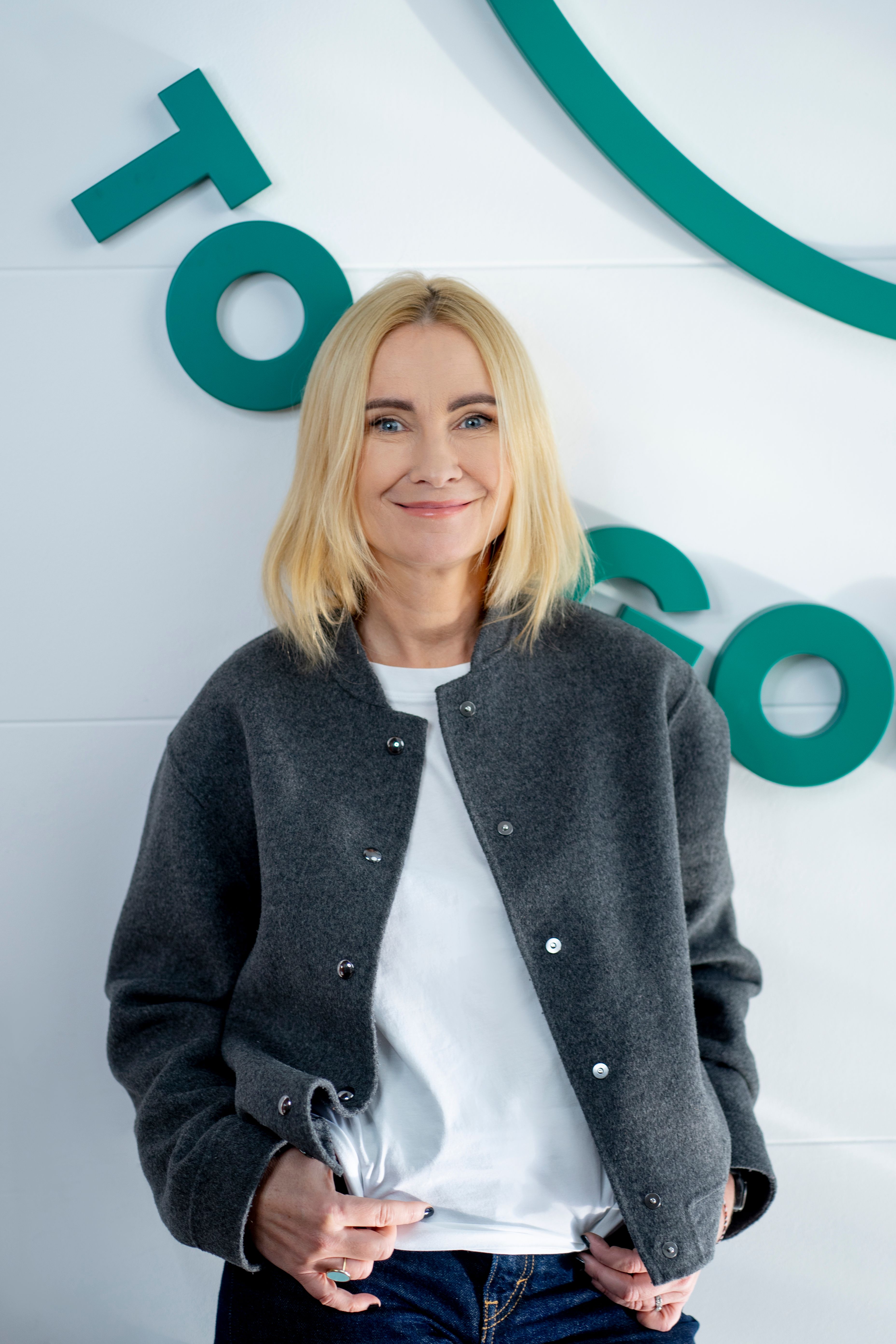 a woman in a blue ruffled top smiles for the camera
