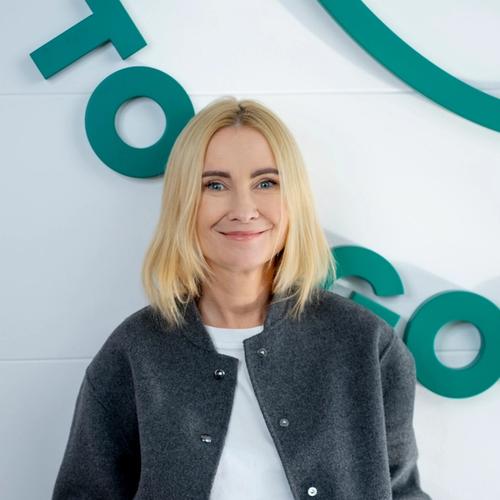 a woman in a blue ruffled top smiles for the camera