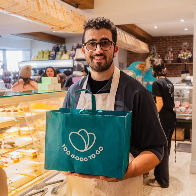 Un uomo tiene in mano una borsa con la scritta ``troppo buona per andare'' in una panetteria.