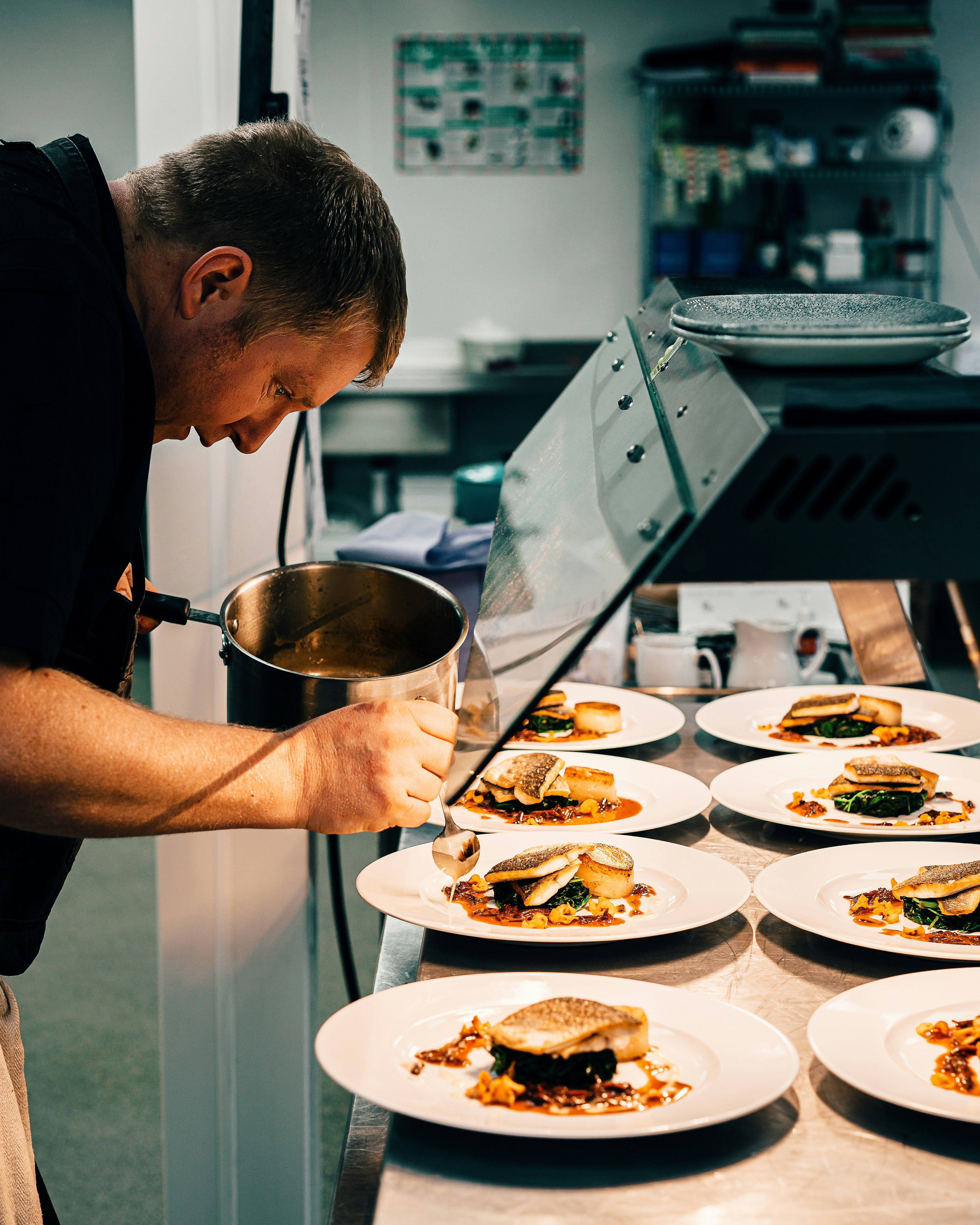 a chef is preparing dishes lined up in a professional kitchen