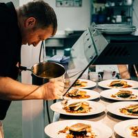 a chef is preparing dishes lined up in a professional kitchen