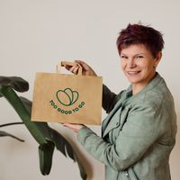 a woman in a green suit and white shirt is standing in front of a plant .