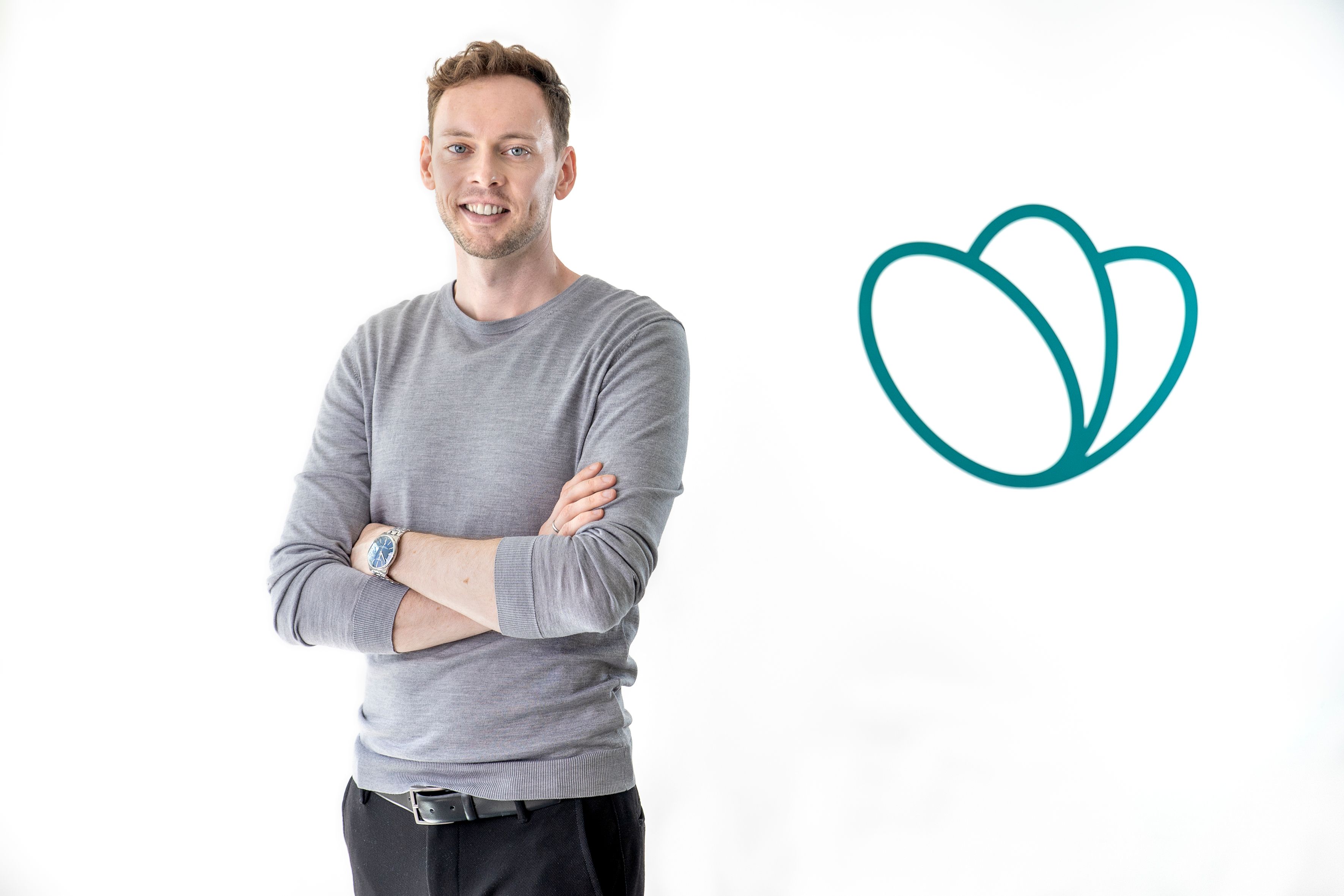 a man is standing with his arms crossed in front of a heart icon .