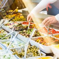 an assortment of foods in trays displayed in a counter with spoons