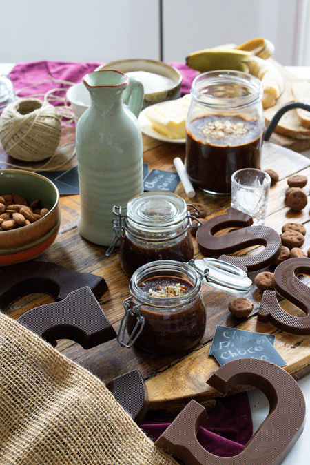 a jar of chocolate sauce sits on a wooden table