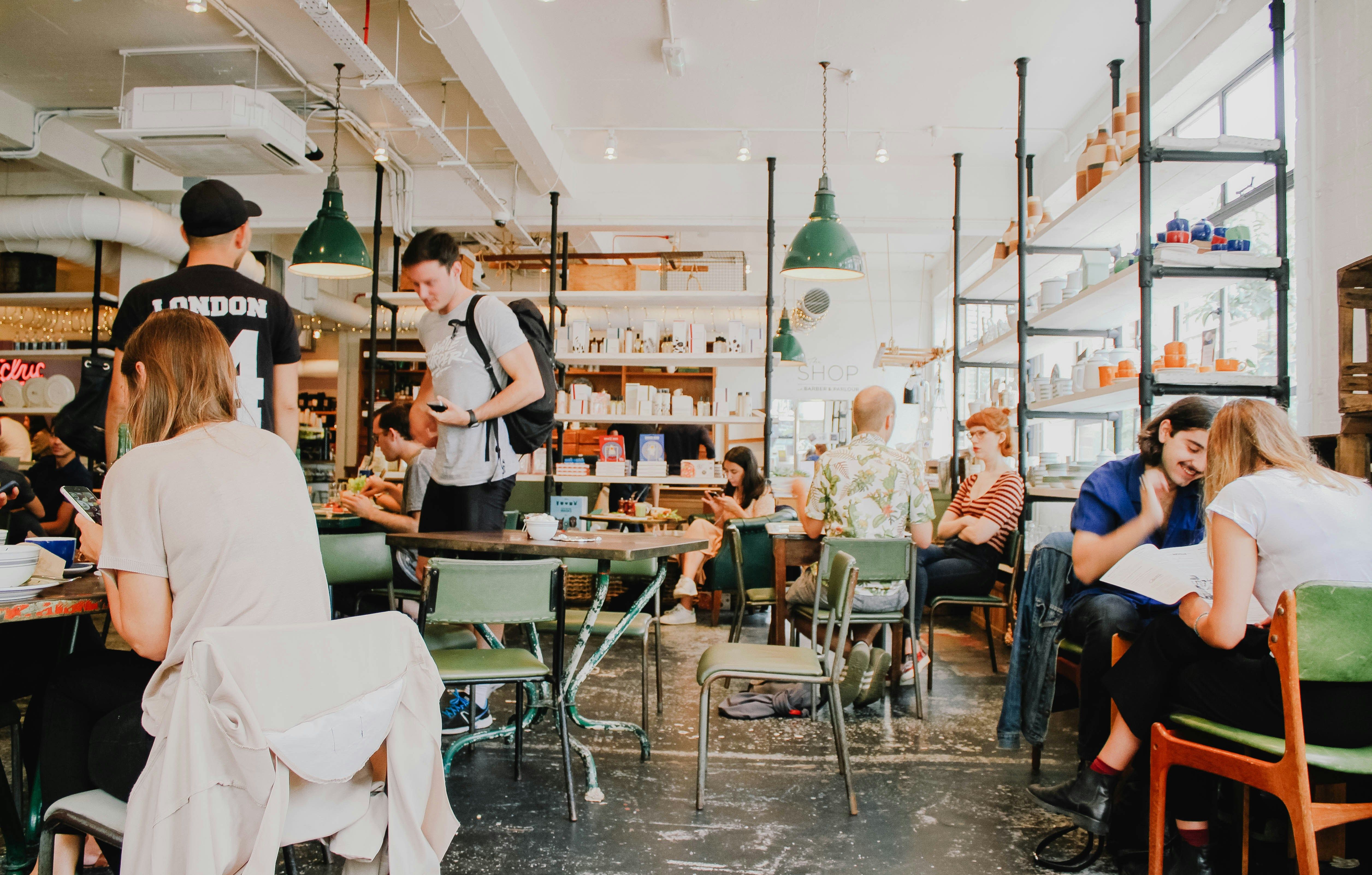 a group of people are sitting at tables in a restaurant .