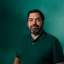 a man with a beard wearing a green polo shirt is standing in front of a green wall .