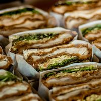 cut sandwiches containing greens and meat wrapped in paper