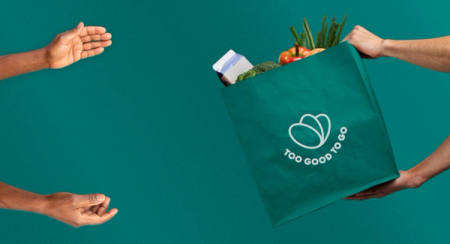Hands exchanging a Too Good To Go bag full of groceries.