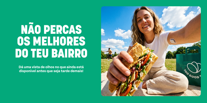 A smiling woman holds a large sandwich in a park with a 'Too Good To Go' bag. Text on a green background reads: 'NÃO PERCAS OS MELHORES DO TEU BAIRRO. Dá uma vista de olhos no que ainda está disponível antes que seja tarde demais!'