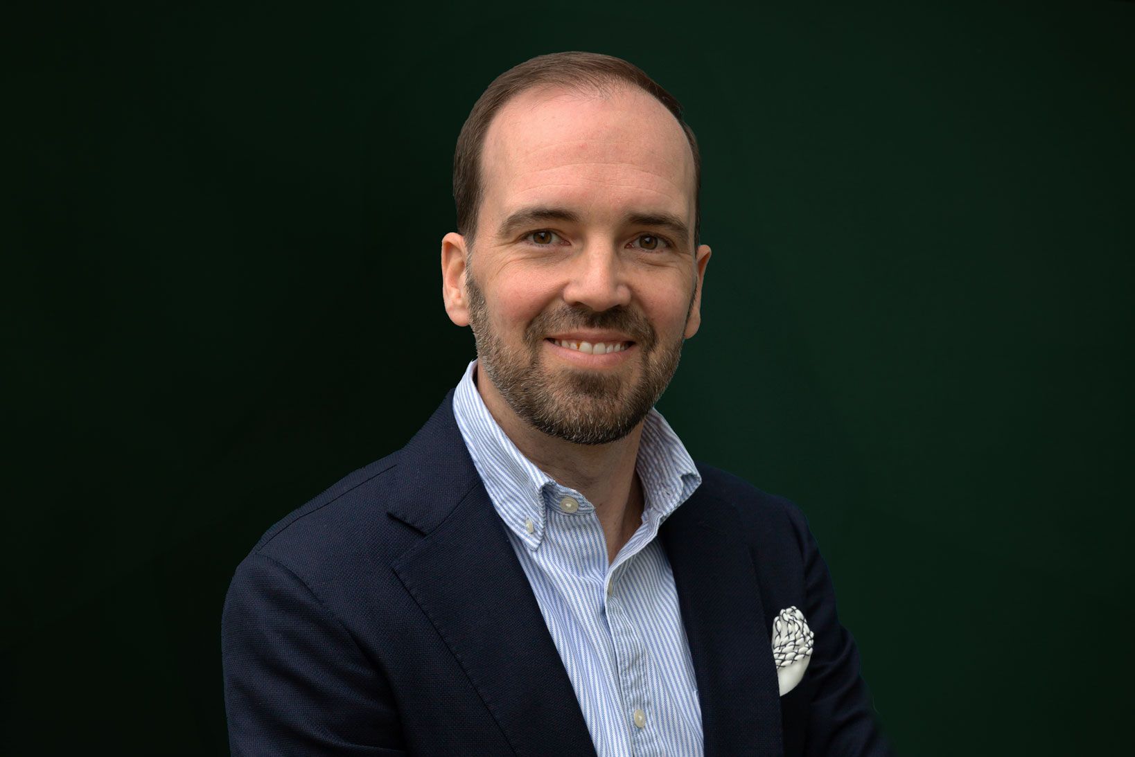 a man with a beard is wearing a suit and smiling for the camera .