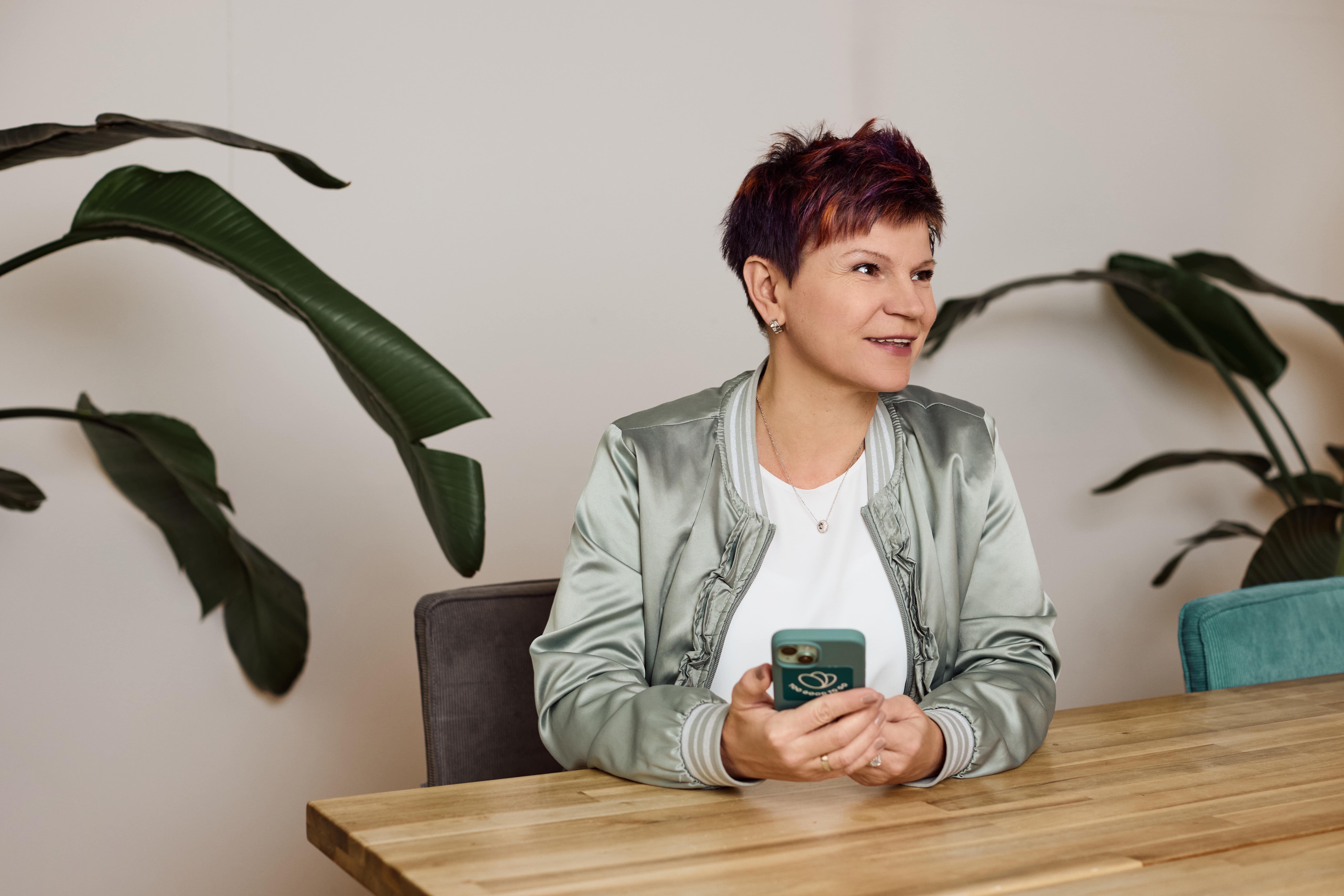 a woman is sitting at a table holding a cell phone .