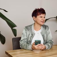 a woman is sitting at a table holding a cell phone .