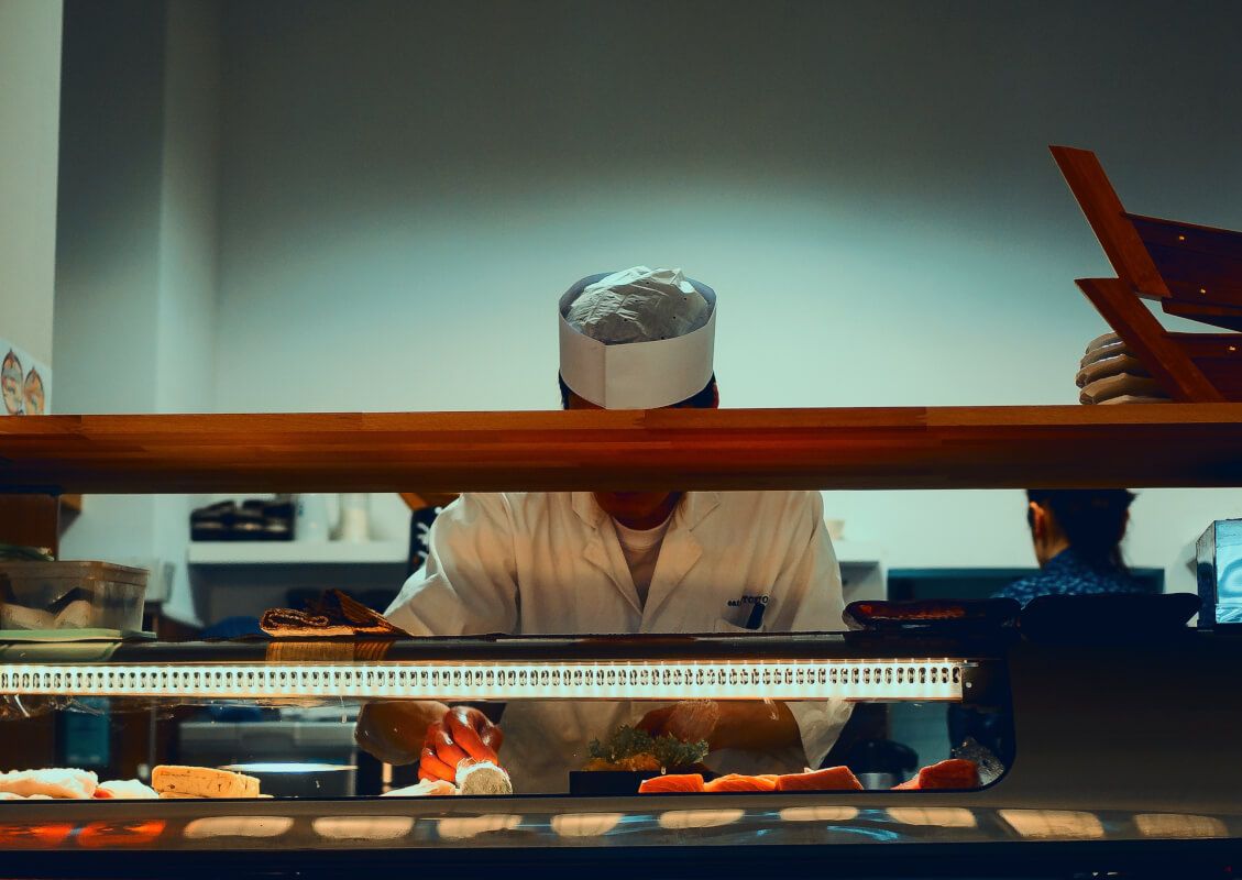 a chef is preparing sushi in a restaurant kitchen .