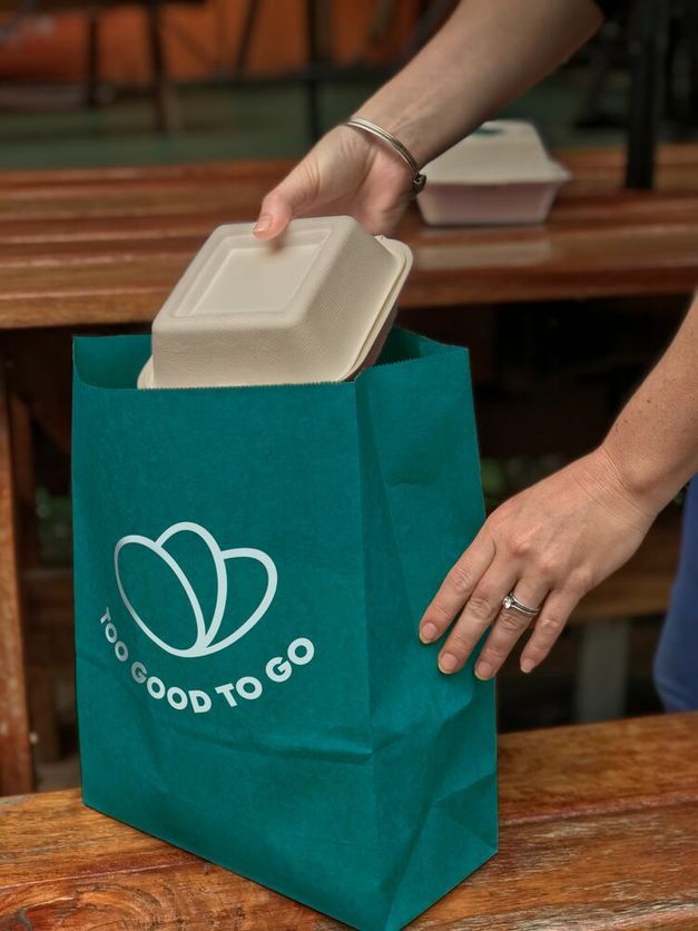 a person is taking a container out of a too good to go bag .