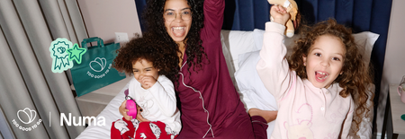 A joyful woman and two children in pajamas celebrate together on a bed, with "Too Good To Go" branding and "Numa" text.