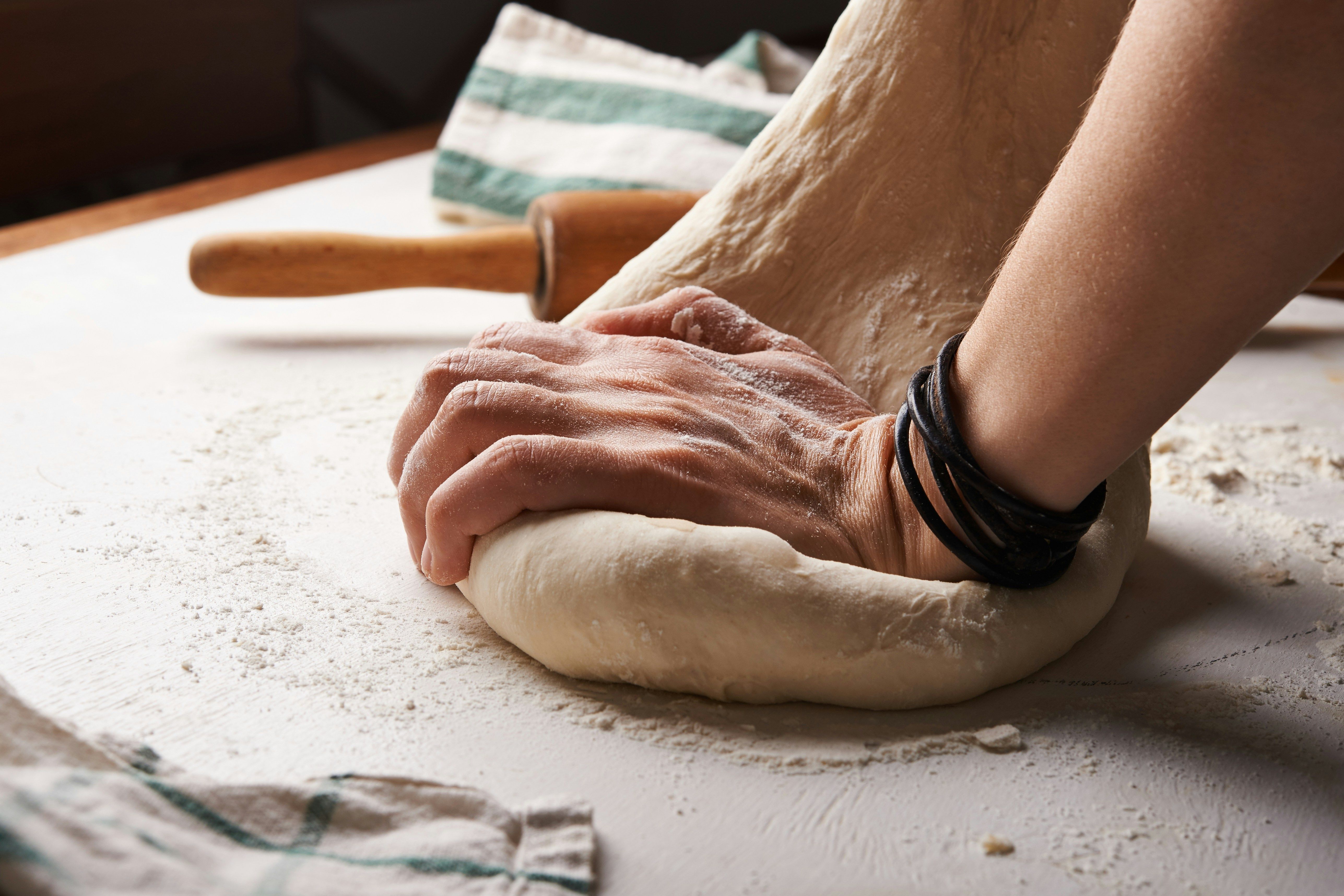 a person is kneading dough on a table with a rolling pin