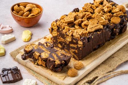 Chocolate kruidnoten loaf cake, sliced to show layers, surrounded by a bowl of kruidnoten and chocolate shapes.