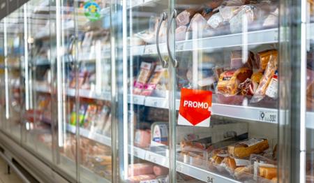 Supermarket refrigerated display case filled with packaged meats, featuring a red "PROMO" sign.