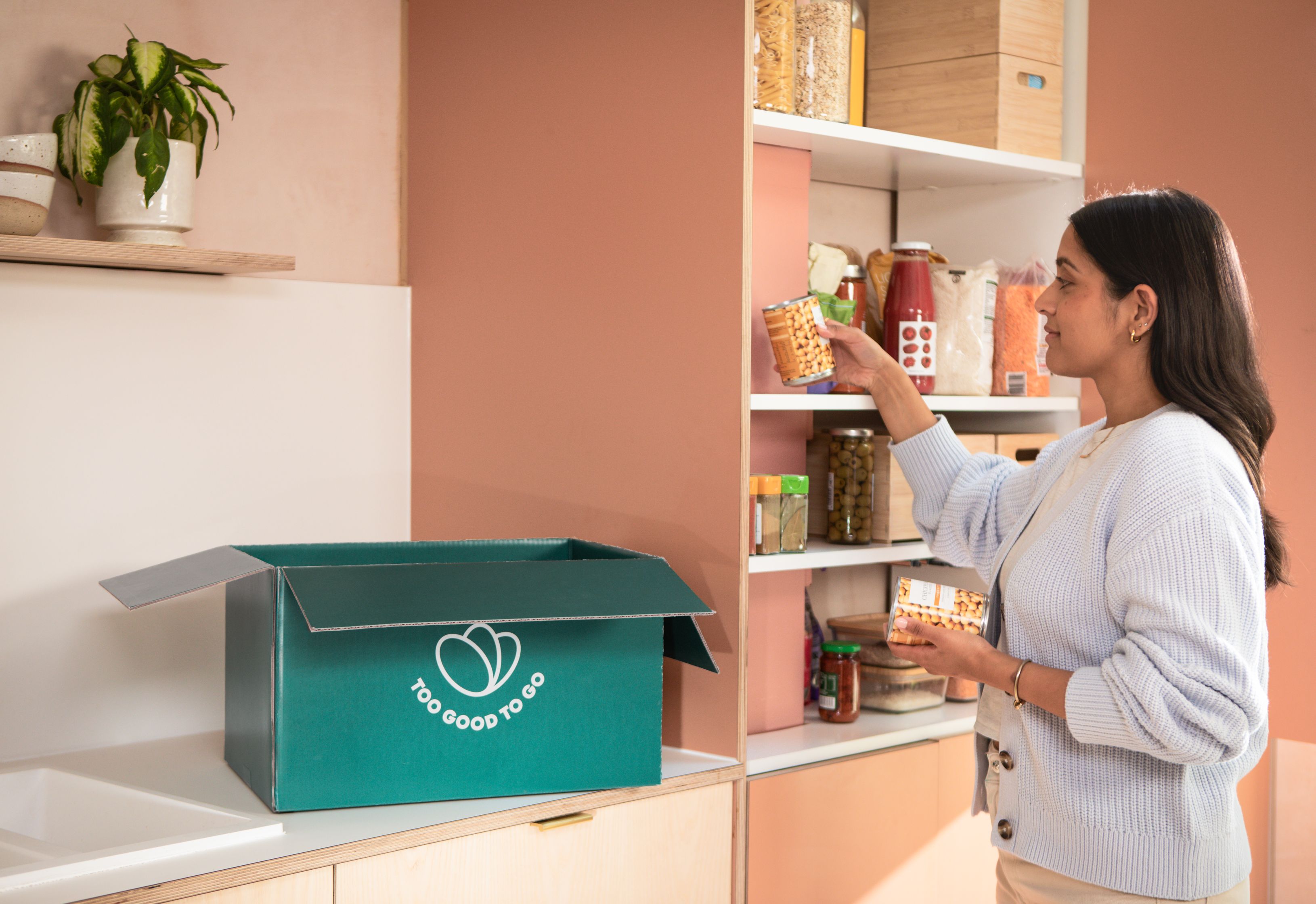 a woman is standing in a kitchen looking at a box of food .