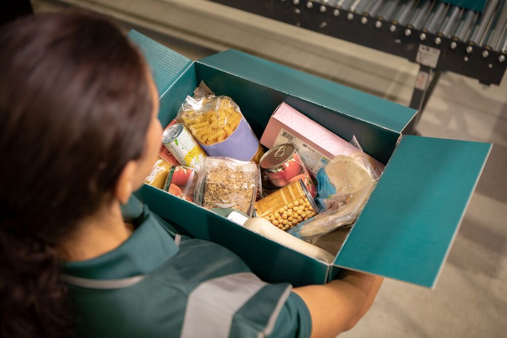 a woman is holding a box filled with food .