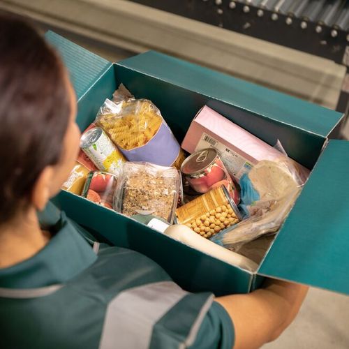 a woman is holding a box filled with food .